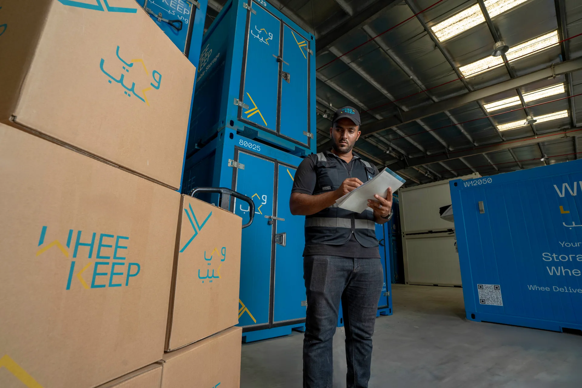 A WheeKeep staff member checking a list among boxes and storage units