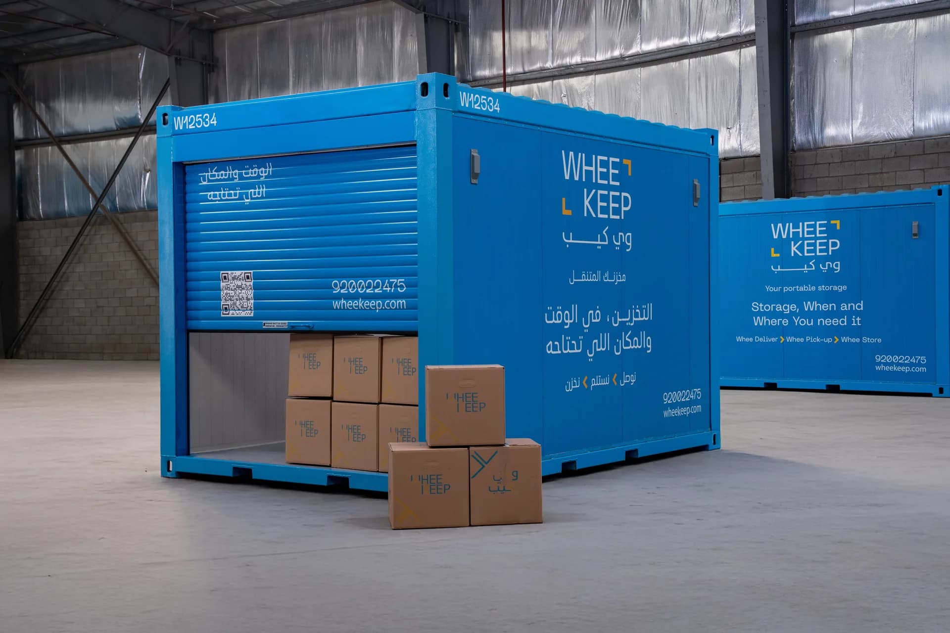 A WheeKeep unit with its roll-up door half open and boxes in front, inside the facility